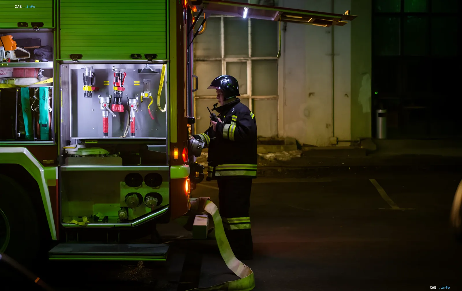 Пожарный в защитной форме работает у пожарной машины ночью во время тушения пожара после дрон-удара по оккупированным территориям