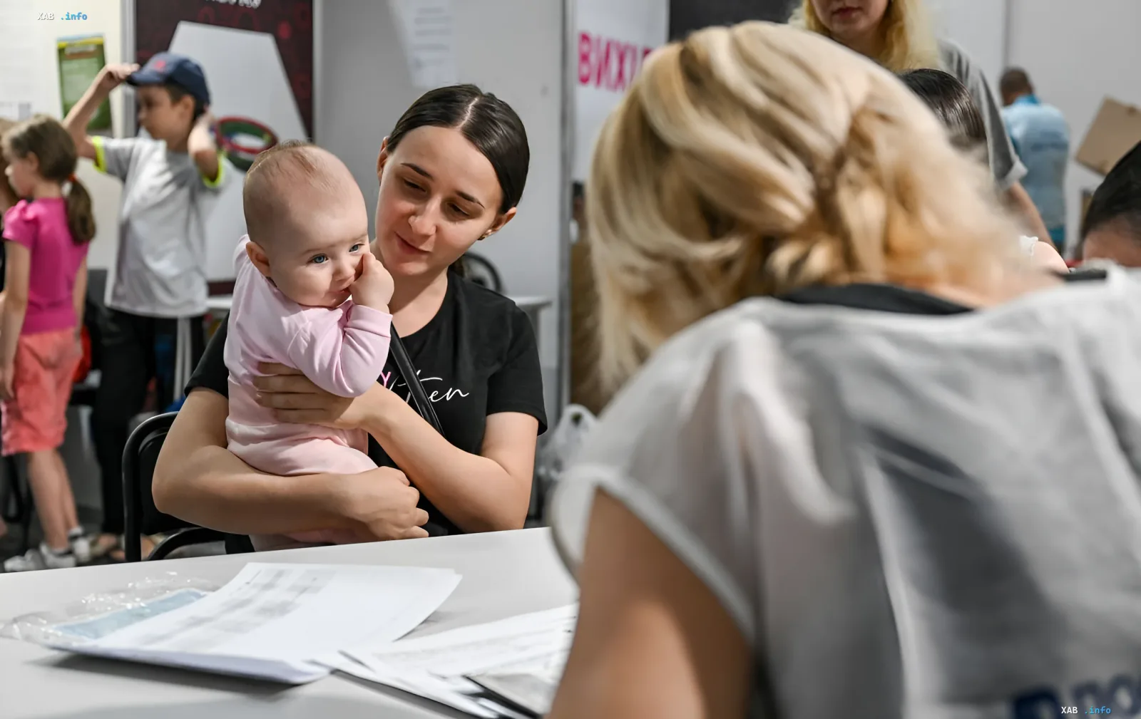 Mother with infant filling out documents at a refugee registration center