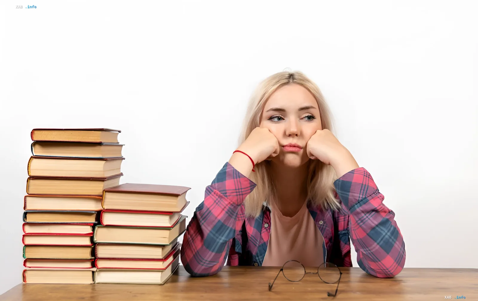 Girl with a tired expression sitting at a desk with books, symbolizing the pressure of the educational system and the need to protect youth in the context of the petition to raise the age of consent