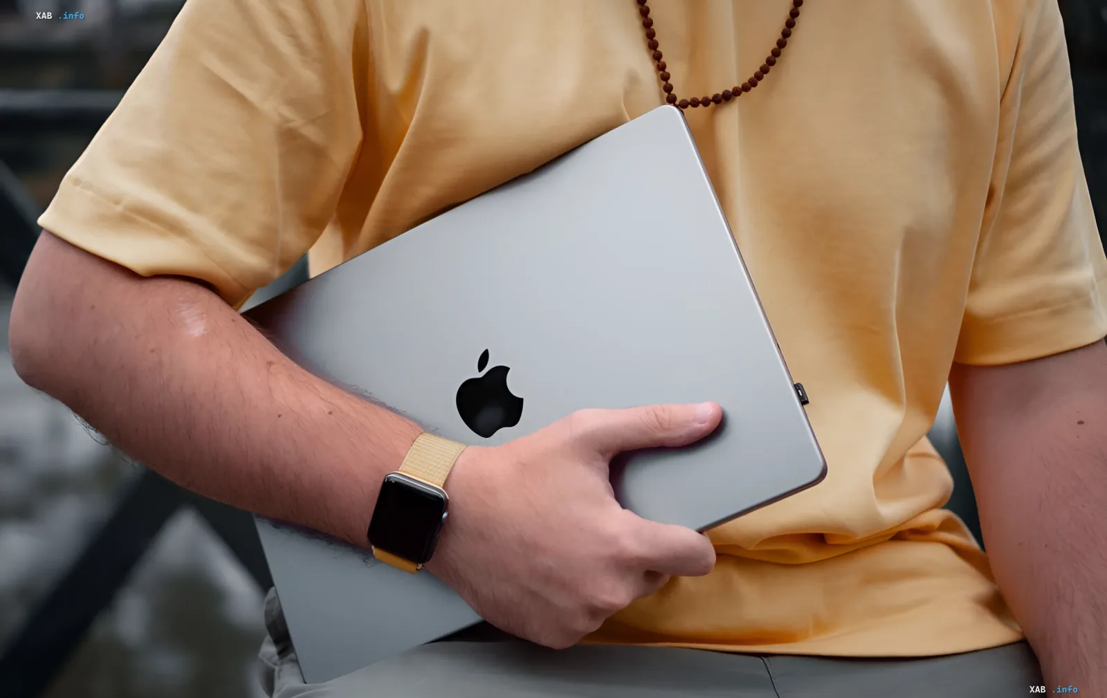 Человек держит серебристый MacBook с логотипом Apple, символизируя рост цен на технику Apple в Украине