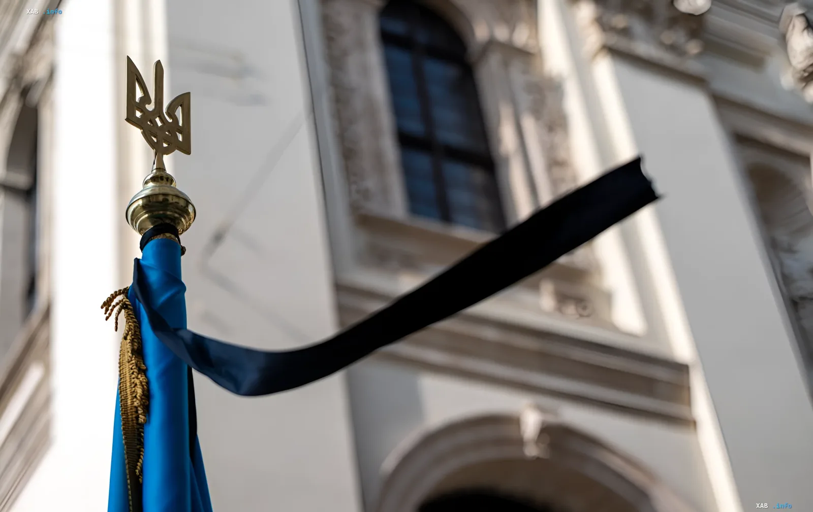 Ukrainian flag with black mourning ribbon in front of a building in Kyiv after massive attack in Darnytskyi district