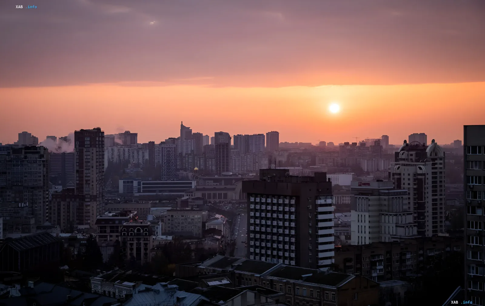 Захід сонця над міським пейзажем України: висотки та житлові будинки на фоні помаранчевого неба — метафора мрії про власну квартиру для штукатурів та охоронців
