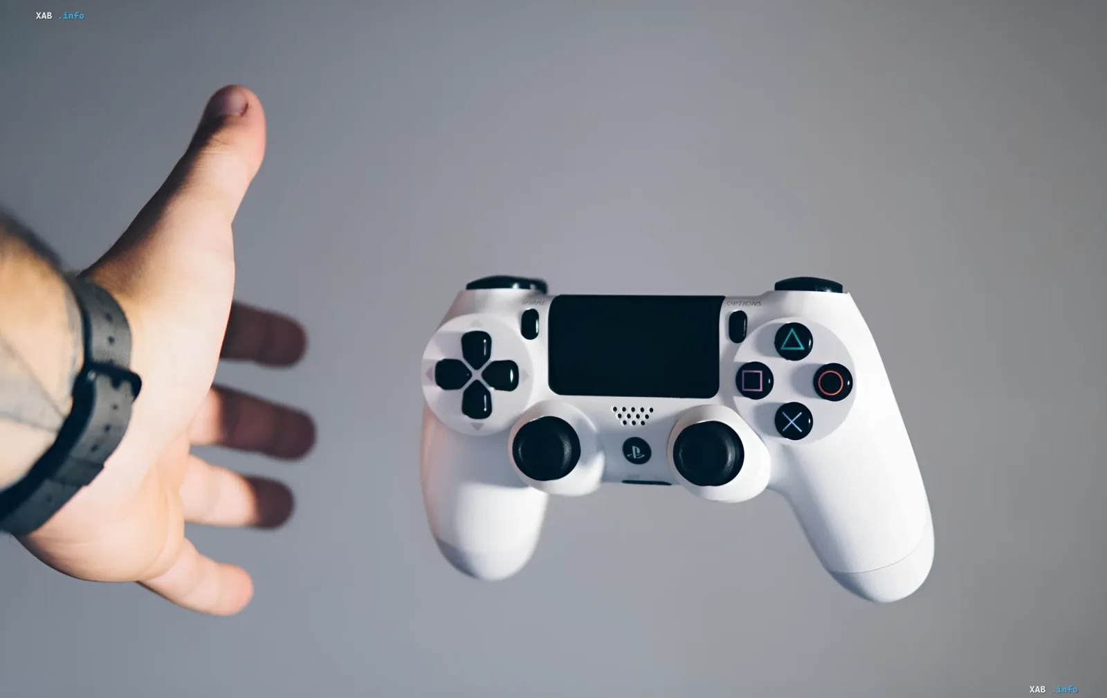 Белый контроллер PlayStation 5 и рука, достигающая его — символ перехода от физических дисков к цифровым играм