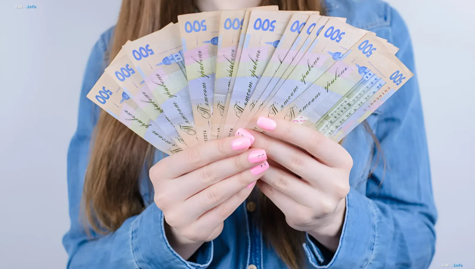 Женщина держит веер из купюр в 500 гривен — символ финансовой поддержки украинцев через субсидии на дрова и уголь зимой