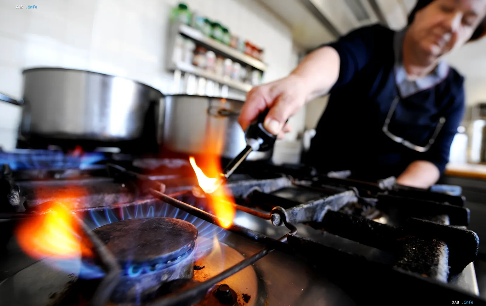 Koch kocht auf einem Gasofen mit hellem Flammen, illustriert das Thema stabiler Tarife und sinkender Marktpreise für Gas im Juli