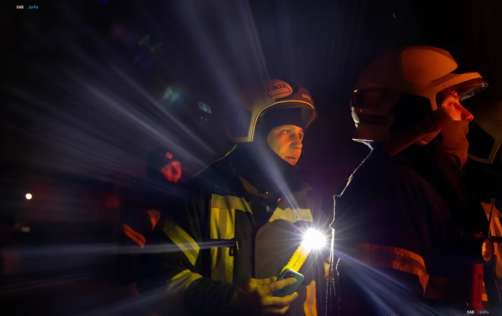 Rescuers in protective gear with flashlights at the site of the strike on the ambulance station in Kyiv at night