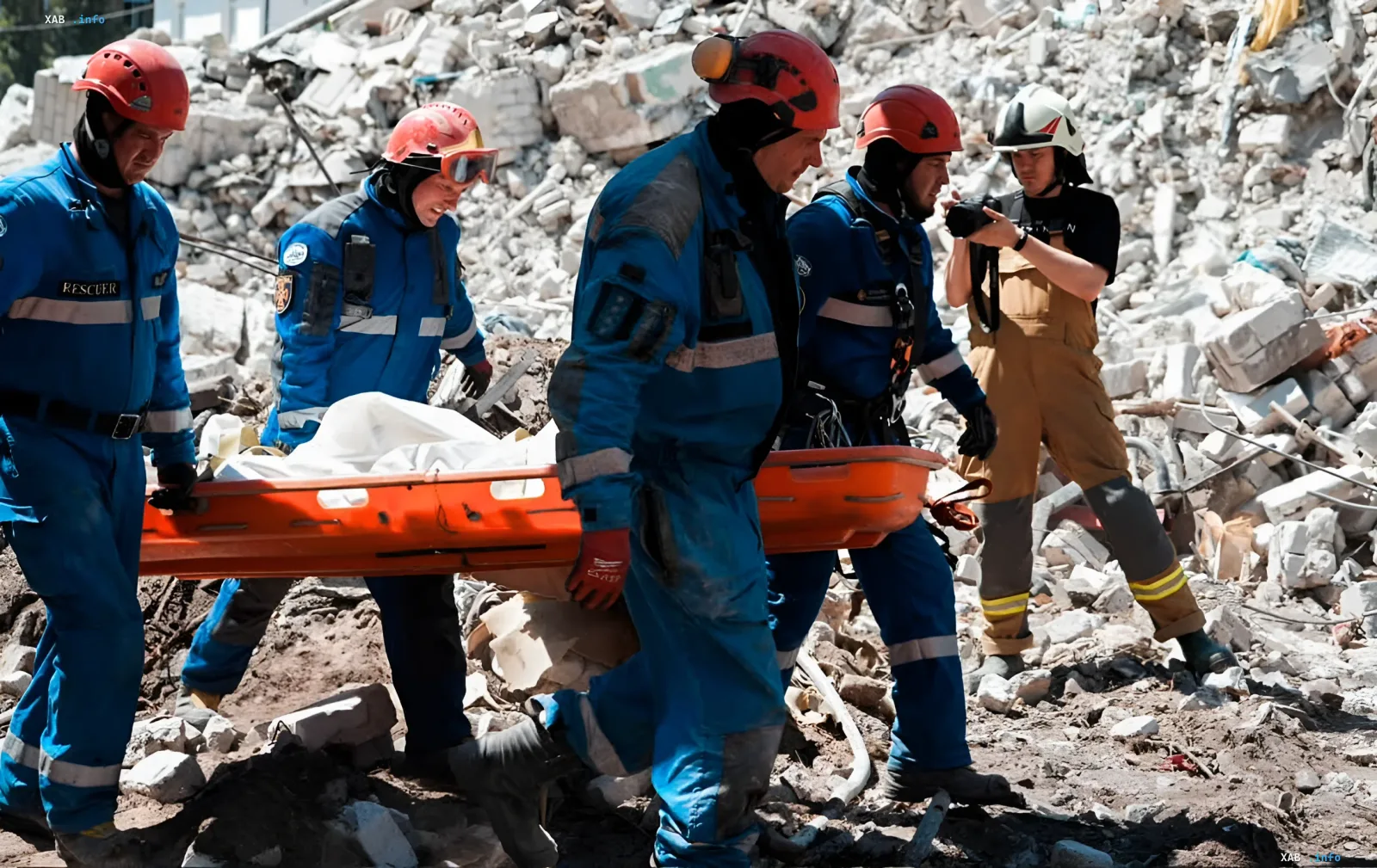 Rescuers in blue uniforms carry a body on stretchers from the rubble of a destroyed building in Kyiv after a missile strike