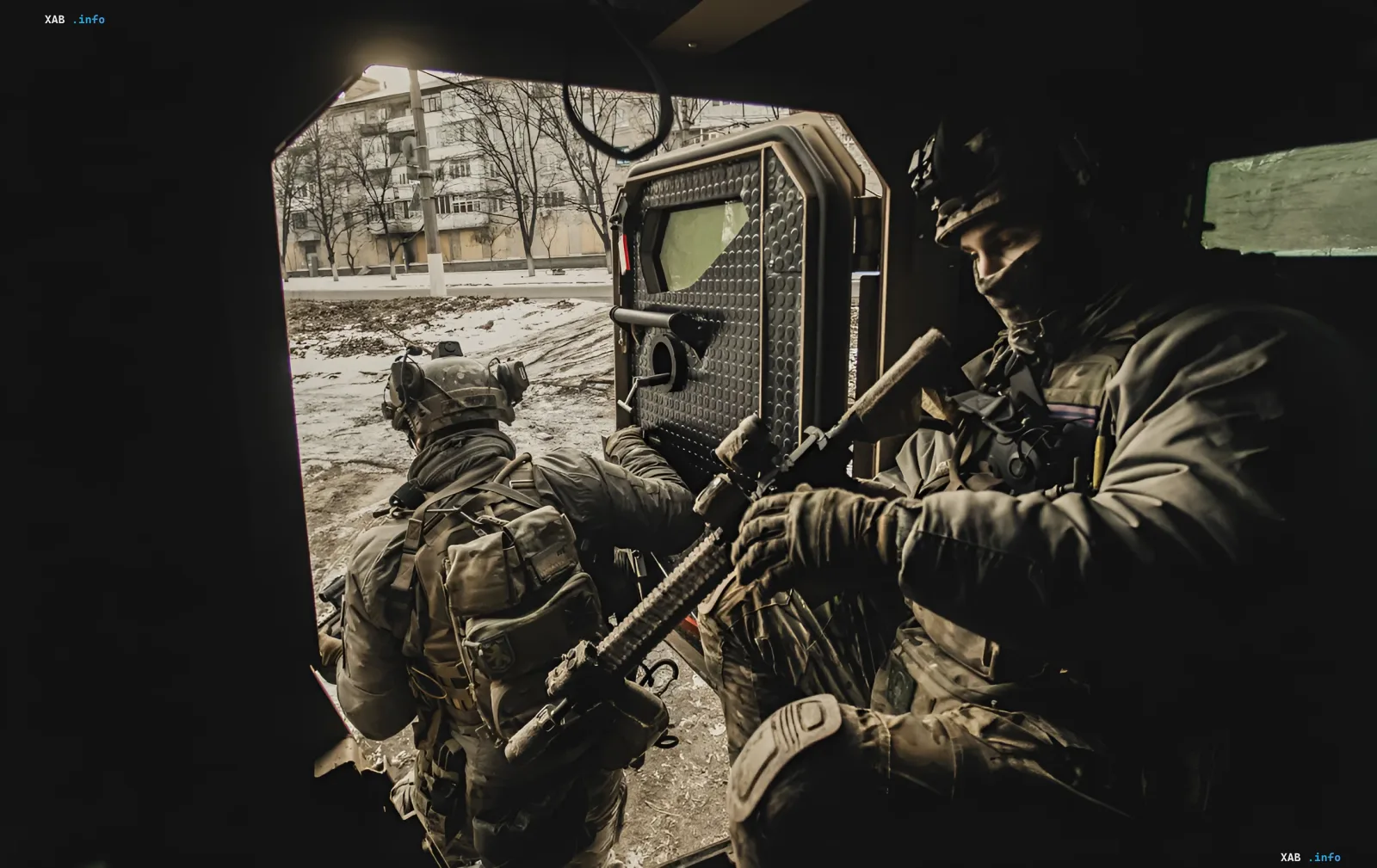 Украинские военные в бронежилетах и шлемах с оружием в руках выходят из бронетранспортера, готовясь к операции на фоне зимнего пейзажа.