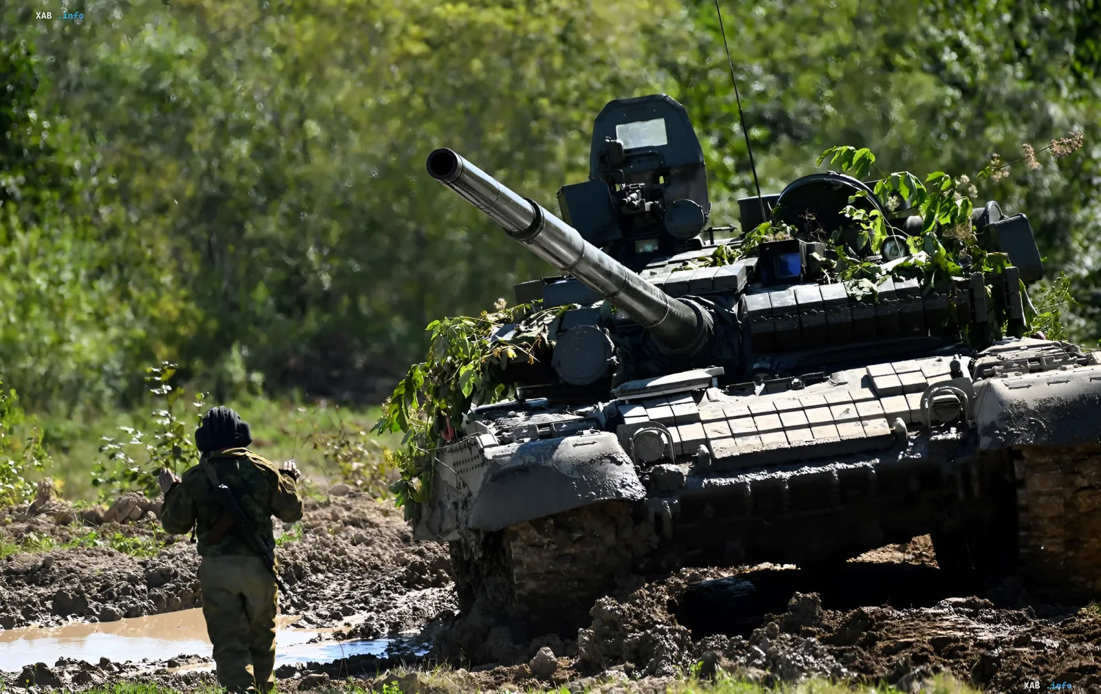 Российский танк Т-72 в лесистой местности с военнослужащим рядом, иллюстрирующий угрозу наземного вторжения