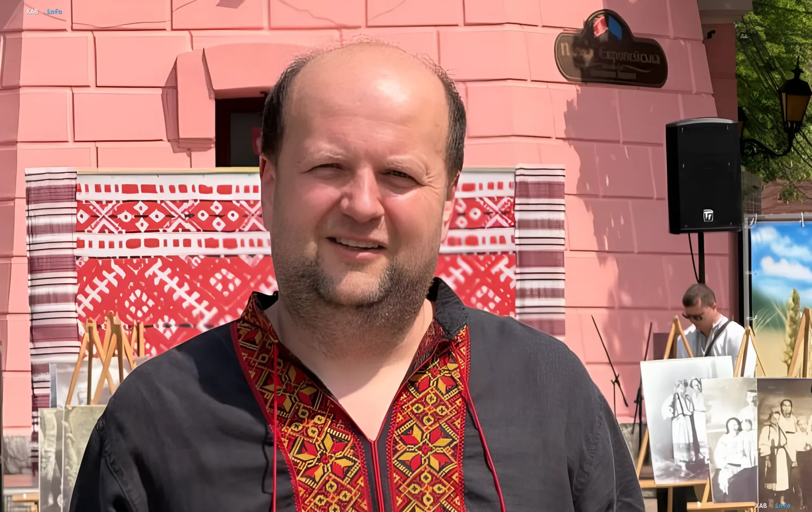 Виктор Бронюк в национальном костюме на фоне выставки, обсуждает проблемы с НМТ своей дочери