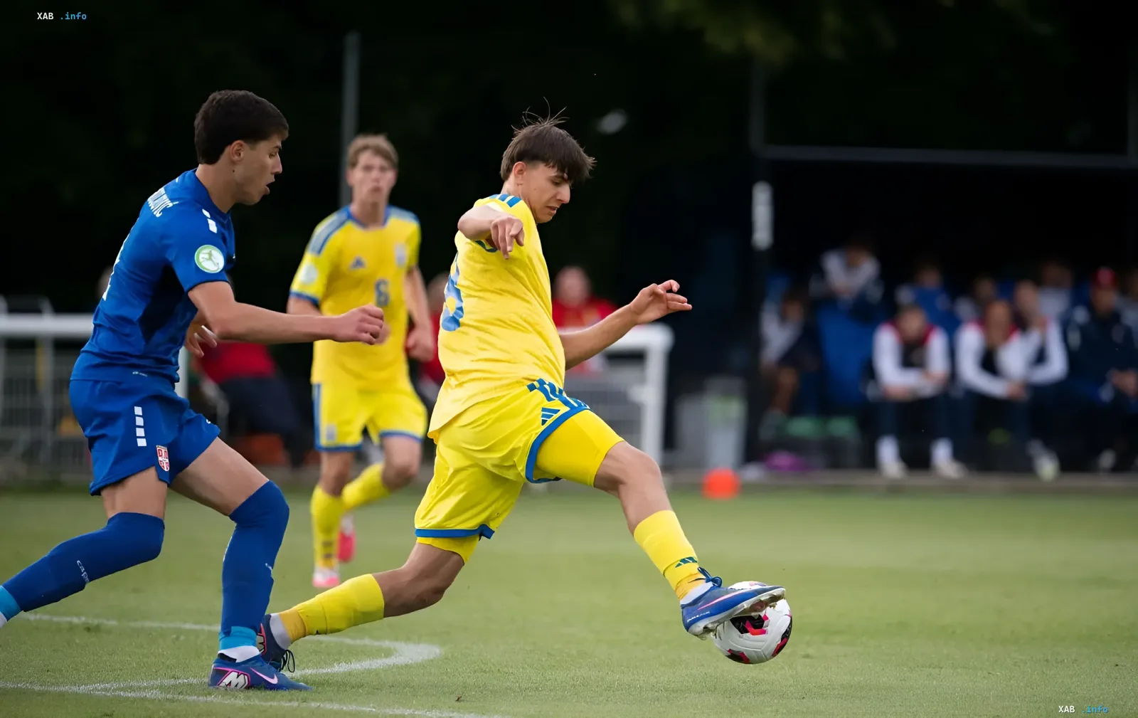 Игрок сборной Украины U-19 в желтой форме контролирует мяч под давлением соперника из Италии U-19 в синей форме — ключевой момент решающего матча Евро-2026