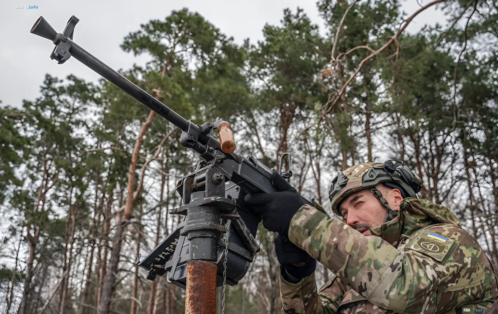 Ukrainian soldier operates PKT machine gun in forest, preparing for defense amid drone attacks