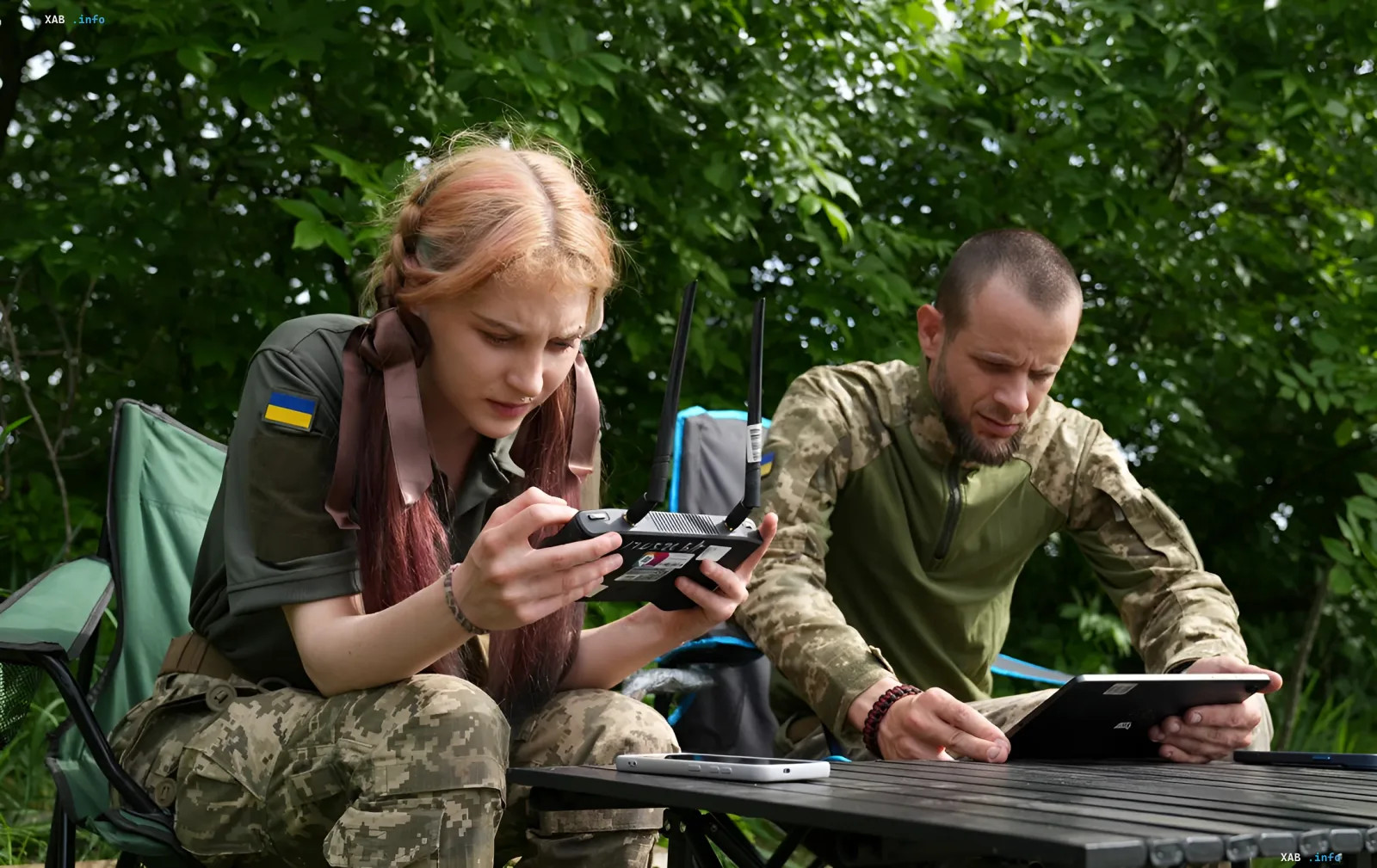 Военнослужащие ВСУ с украинским флагом на рукаве работают с оборудованием для управления дронами, включая пульт с антеннами и планшет, в лесной местности — иллюстрация к новости о дрон-перехватчике APUS-1 от Dark River