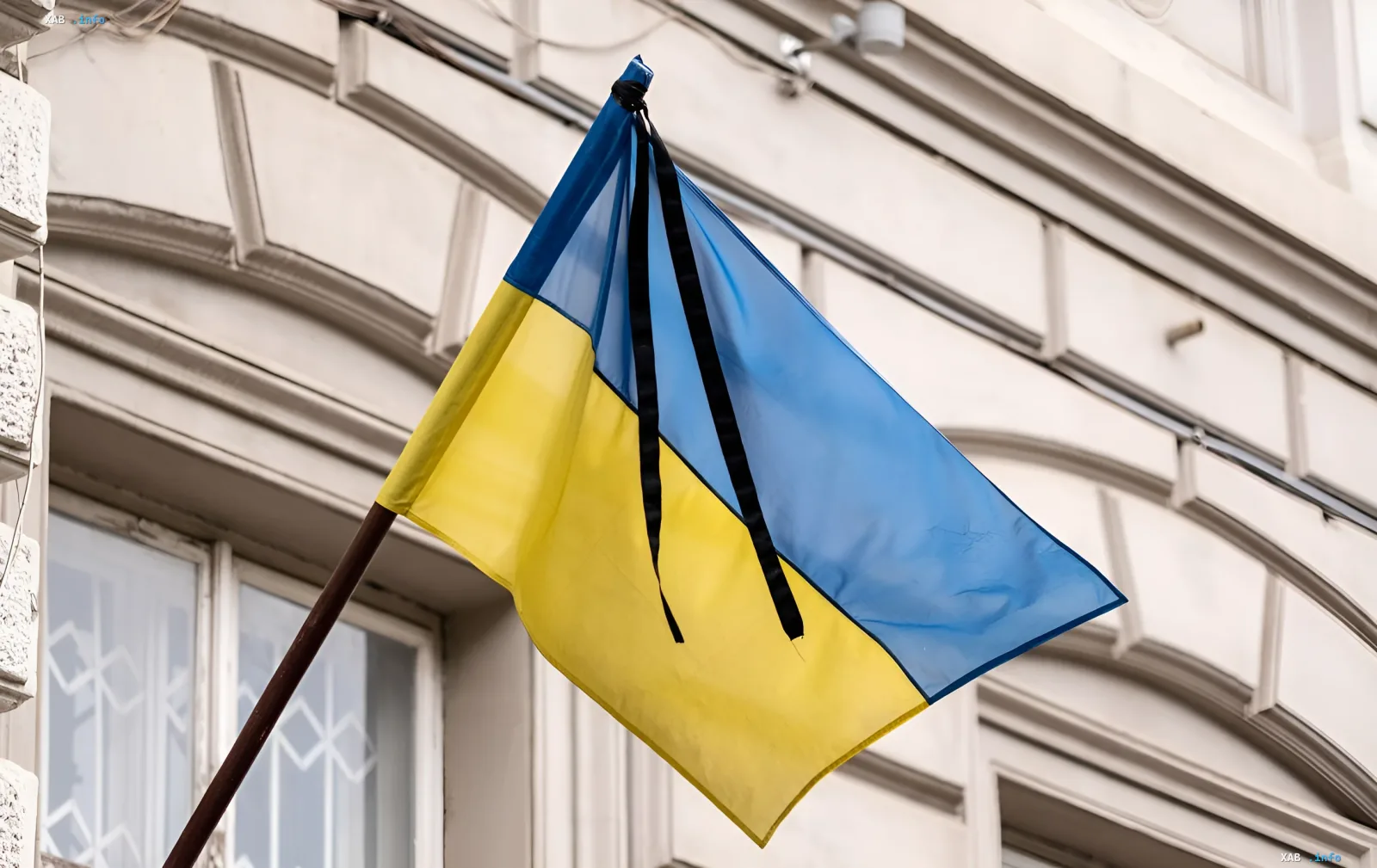 Украинский флаг с черной лентой траура на фоне здания в Киеве после массовой атаки