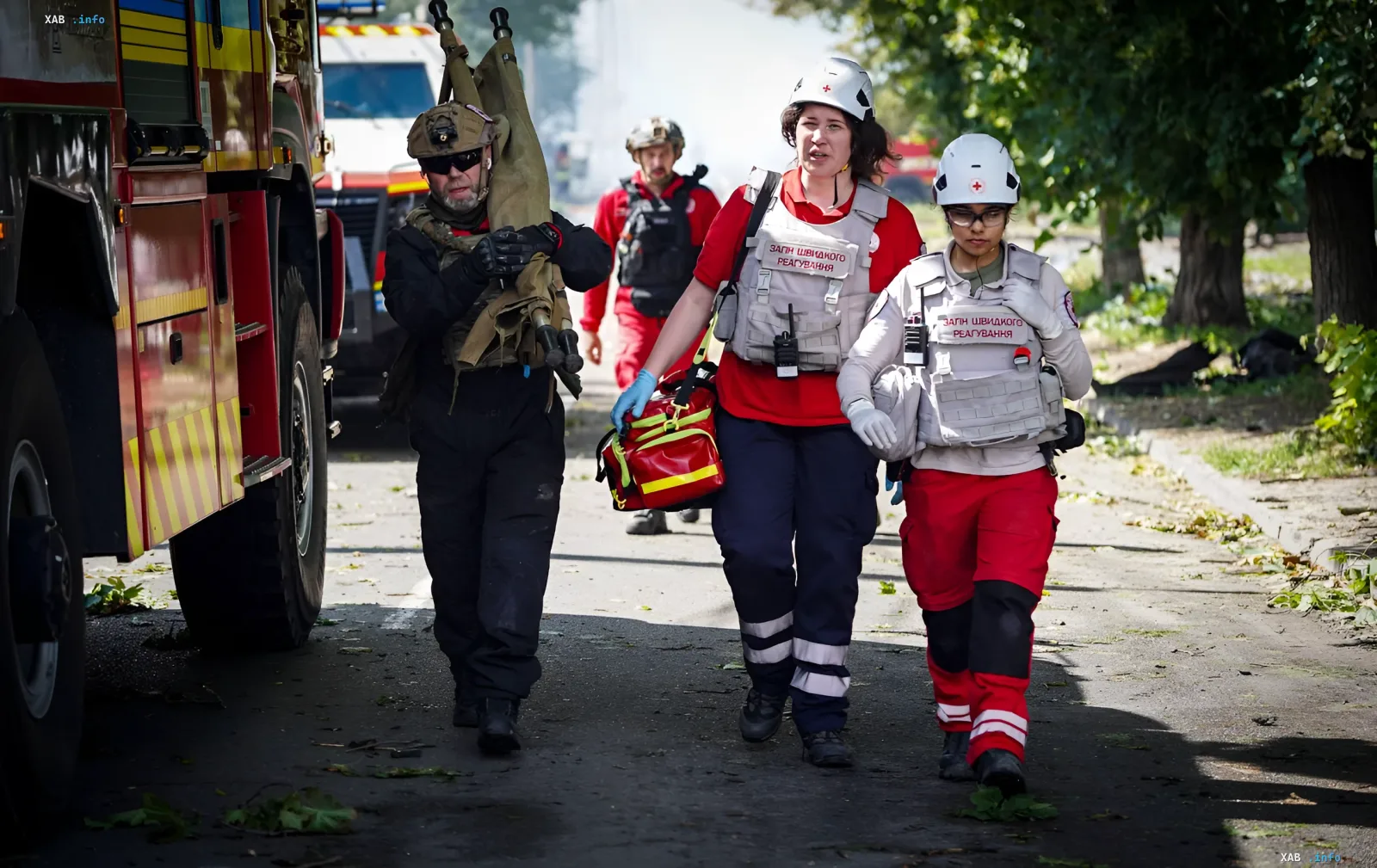 Rescuers and medics in protective vests and helmets carry medical equipment after a massive attack in Vyshneve, Kyiv region