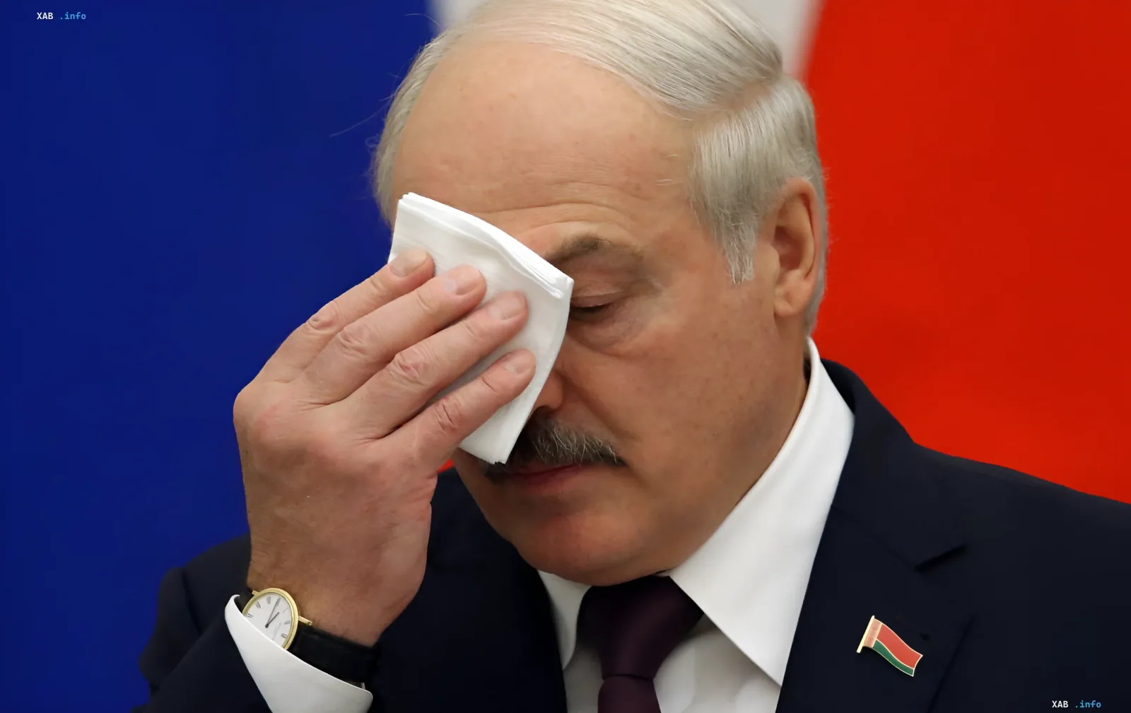 Александр Лукашенко протирает лицо салфеткой на фоне флагов России и Беларуси, выражая усталость или эмоциональное напряжение в контексте заявлений о войне