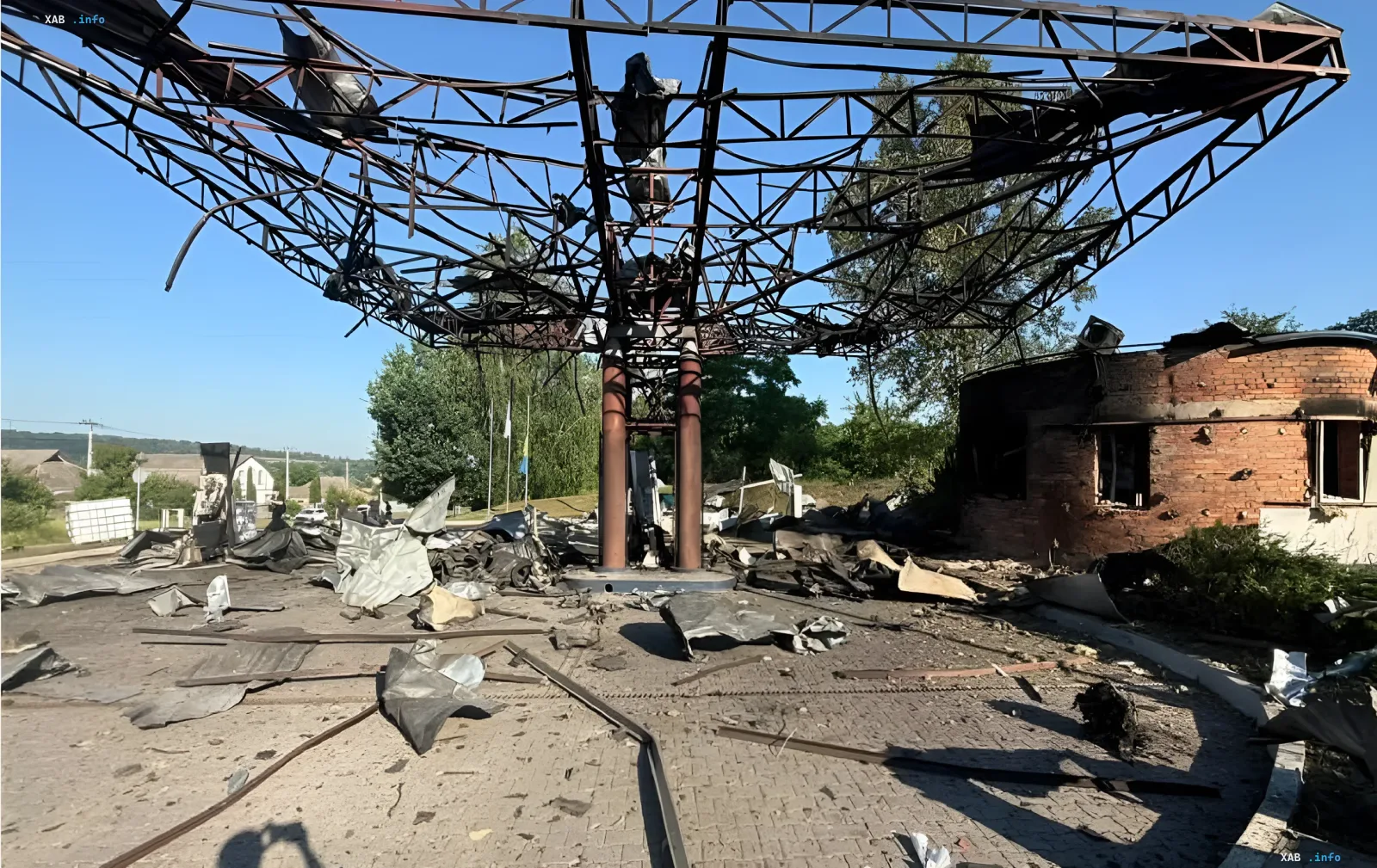 Разрушенная АЗС после удара: обгоревший металлический каркас, обломки и поврежденное здание на фоне ясного неба — последствия атаки по объектам «Укрнафты»