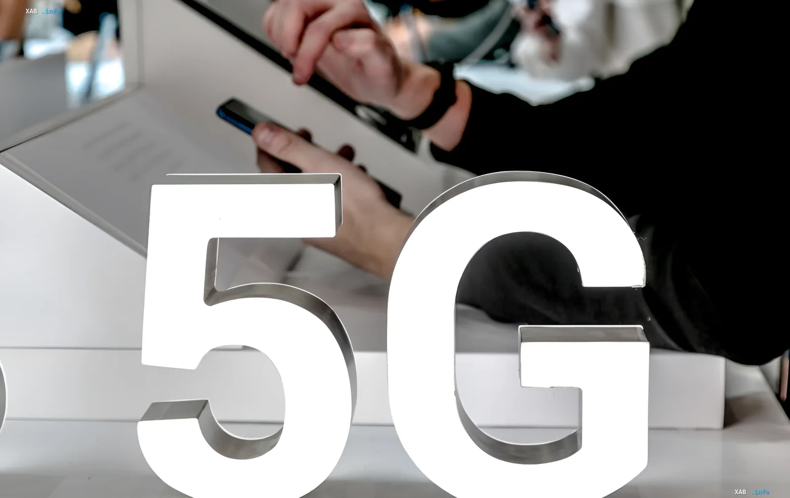 Большая белая надпись 5G на переднем плане, на фоне человек держит смартфон, символизируя подготовку к запуску 5G в Киеве