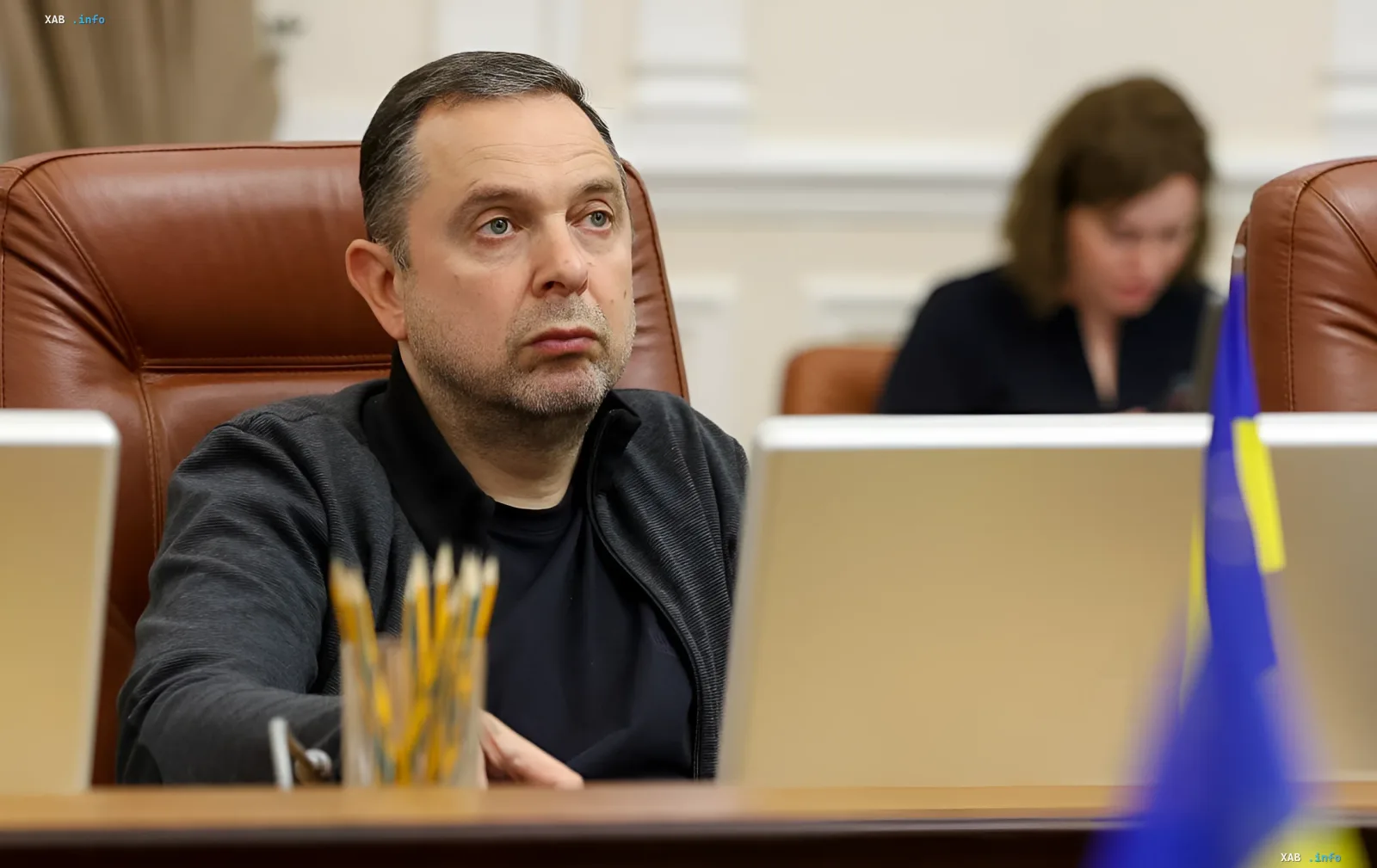 Вадим Гутцайт за столом с ноутбуком и украинским флагом, комментируя решение МОК о допуске россиян к Олимпиаде-2028