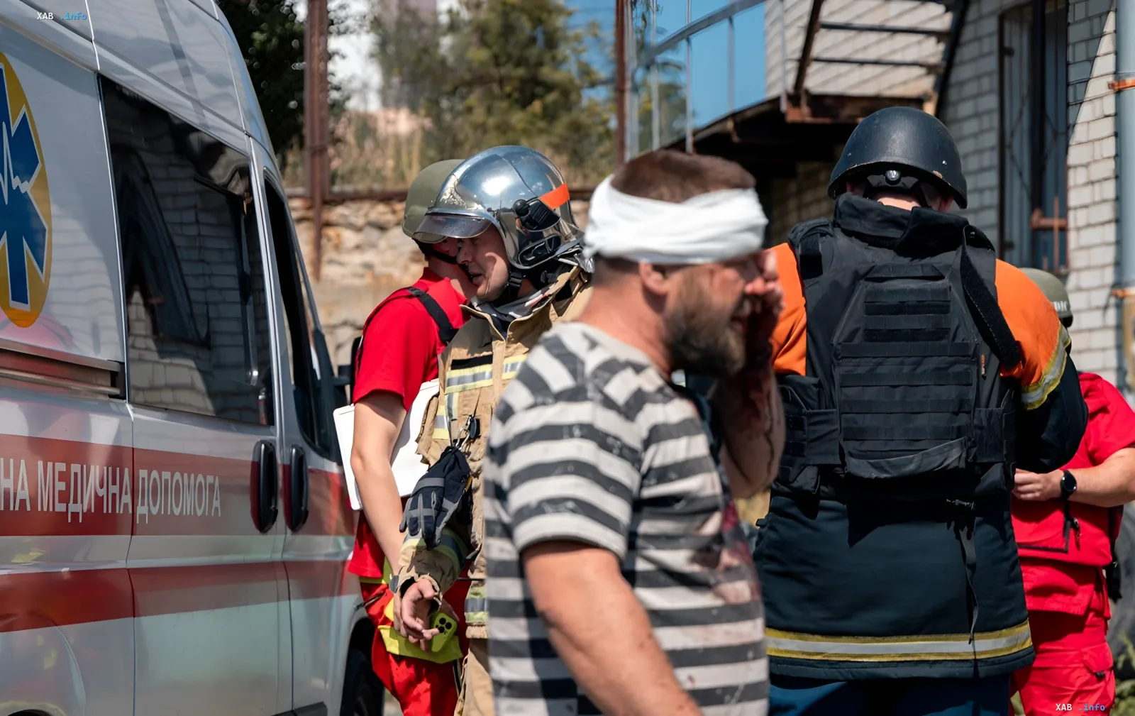 Пострадавший с повязкой на голове рядом с машиной скорой помощи и спасателями после удара по Харькову