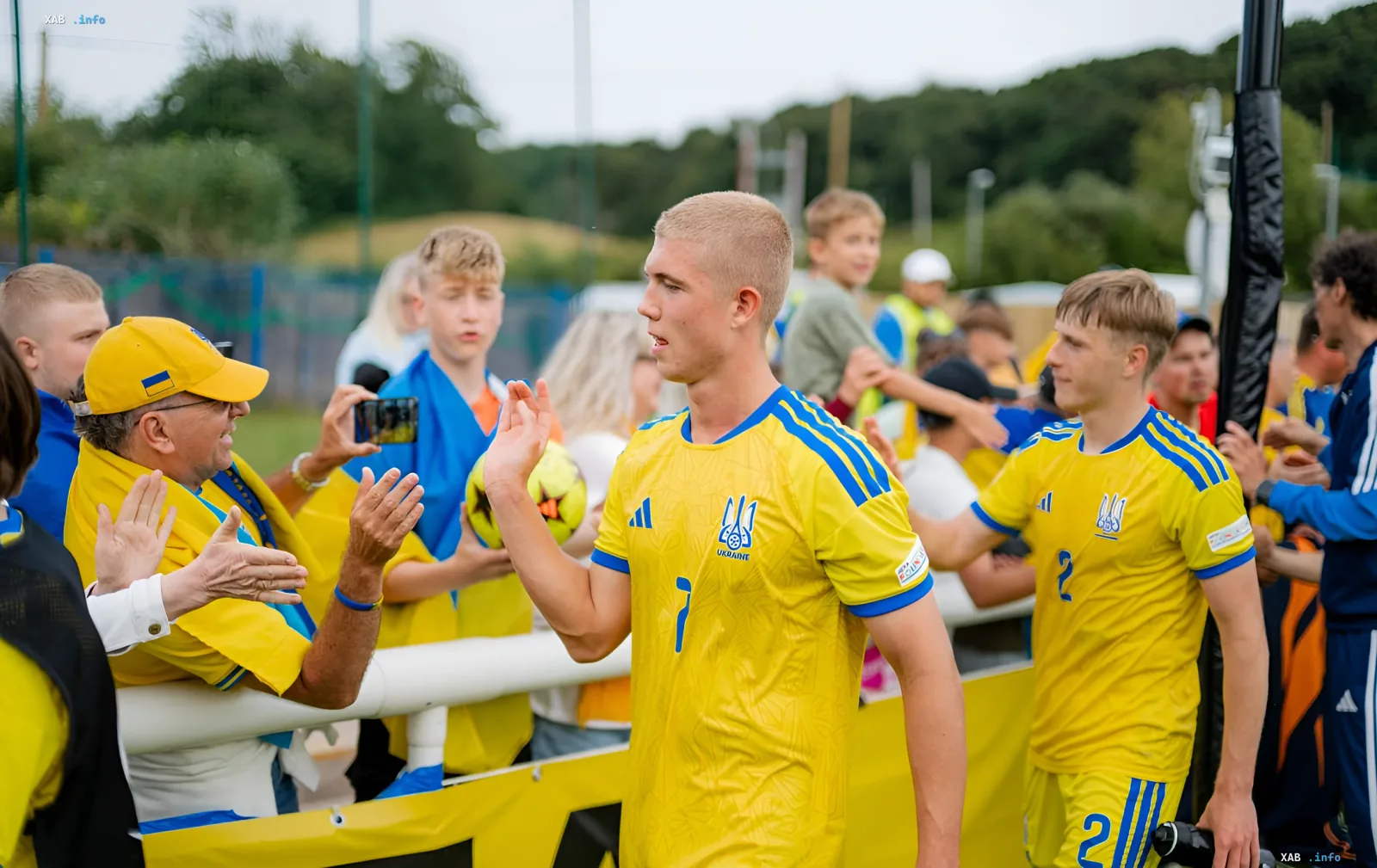Игрок сборной Украины U-19 в желтой форме приветствует болельщиков на фоне трибун