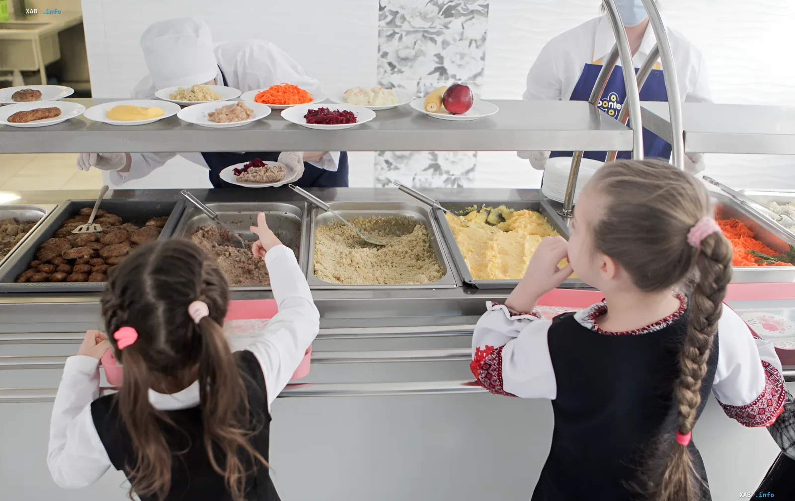 Schoolgirls in a cafeteria choose hot meals from the buffet, illustrating the topic of school meal reform in Ukraine starting in 2026.