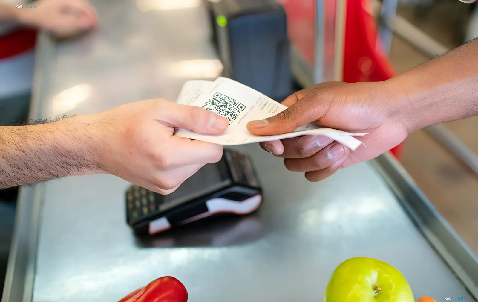 Hands of a customer and cashier exchanging a receipt with a QR code at a supermarket checkout
