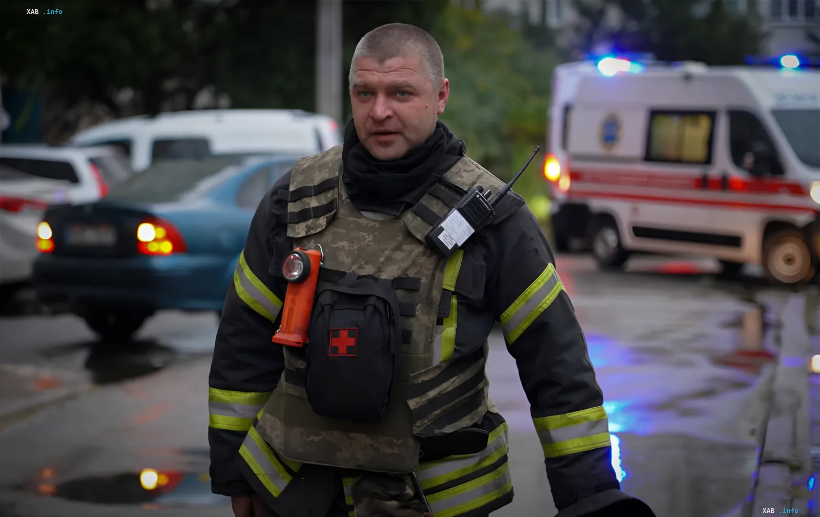 Спасатель в бронежилете и форме МЧС на месте ракетного удара по Одессе, на фоне — машина скорой помощи с мигалками