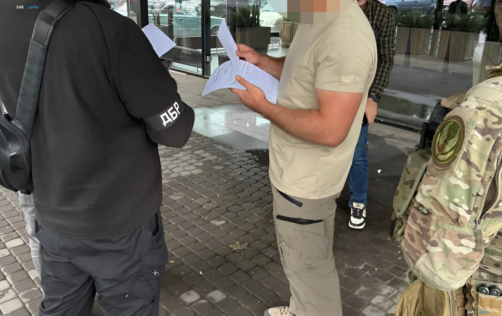 DBR-Beamter mit einem «DBR»-Armband überprüft die Dokumente eines Mannes, der des Schlages eines Kaplan und eines Oberstleutnants verdächtigt wird