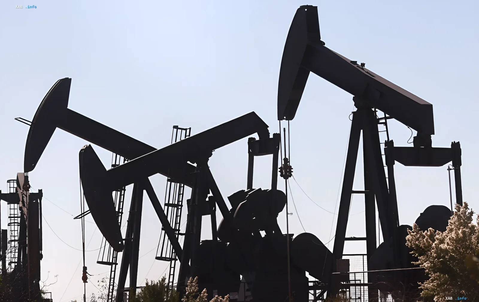 Силуэты нефтяных вышек на фоне неба, символизирующие рост цен на нефть из-за напряженности в Персидском заливе