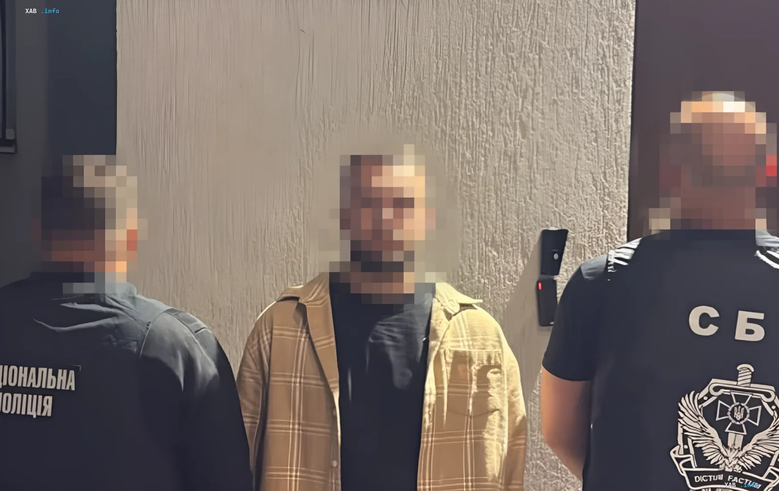 Verhafteter Mann im karierten Hemd zwischen Mitarbeitern der SBU und Nationalpolizei während Operation im Zusammenhang mit Angriff auf TCC in Lwiw
