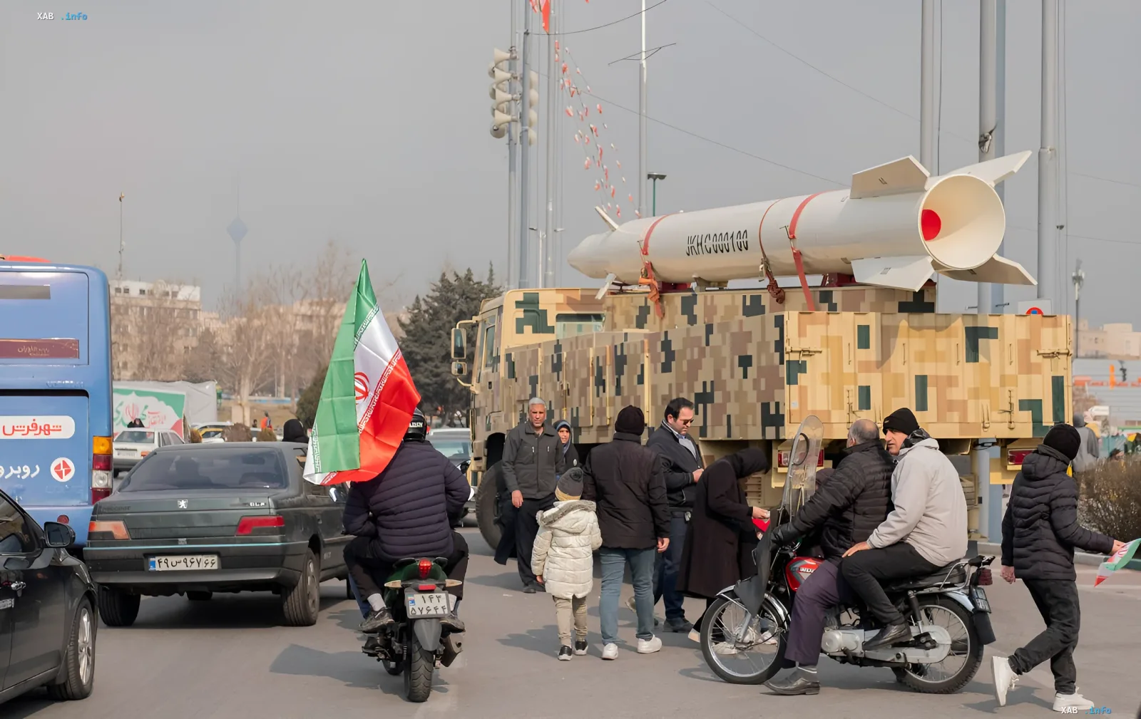 Militärlastwagen mit Rakete und iranischer Flagge vor städtischem Hintergrund