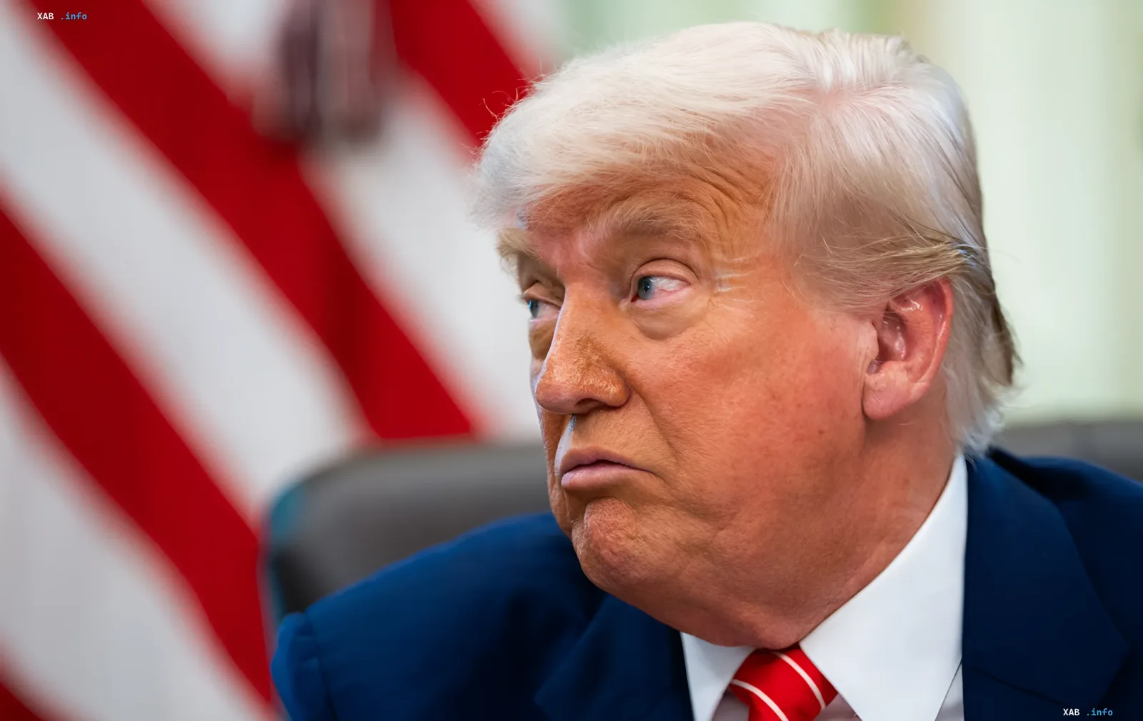 Дональд Трамп в синем костюме с красным галстуком, на фоне американского флага, выглядит задумчиво — в контексте ультиматума Ирану