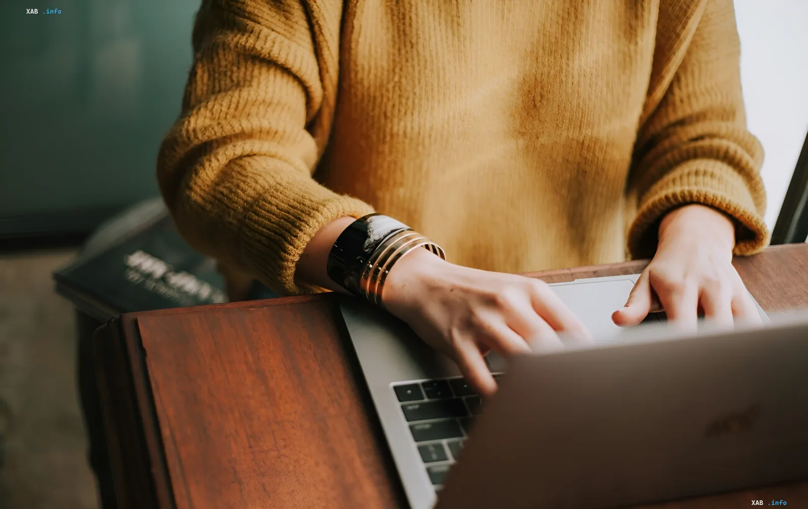 Frau in gemütlichem Pullover arbeitet an silbernem MacBook mit M7-Chip — Symbol für das teuerste Computer-Zeitalter von Apple