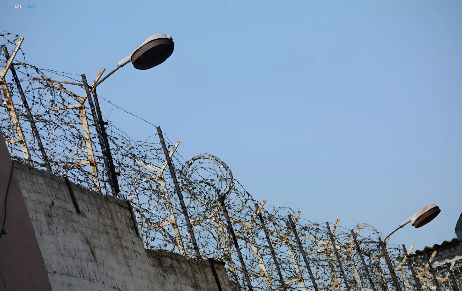 Barbed wire fence and street lamps against a clear sky, symbolizing the torture sites in Olenivka, Pakino, and Taganrog, for which the EU imposed sanctions on 23 individuals and one entity.