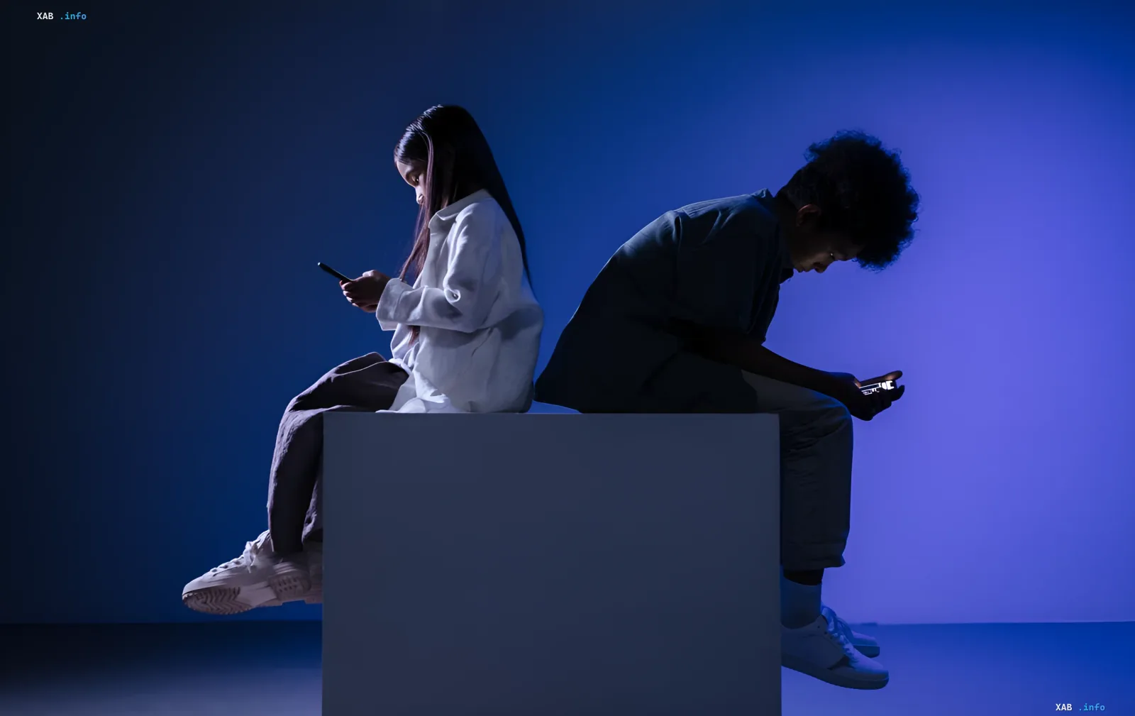 Підлітки сидять спина до спини, захоплено дивляться в смартфони, що символізує цифрову ізоляцію та необхідність регулювання соцмереж для захисту дітей