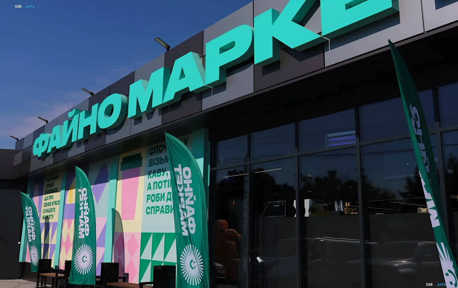 Фасад супермаркета Файно Маркет с яркими зелеными флагами и вывеской на фоне ясного неба