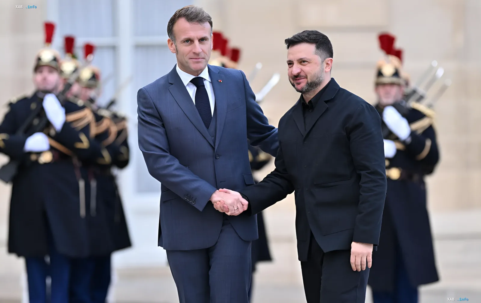 Президент Франции Эммануэль Макрон и Президент Украины Владимир Зеленский пожимают руки на фоне почетного караула во время церемонии награждения Макрона высшей наградой Украины