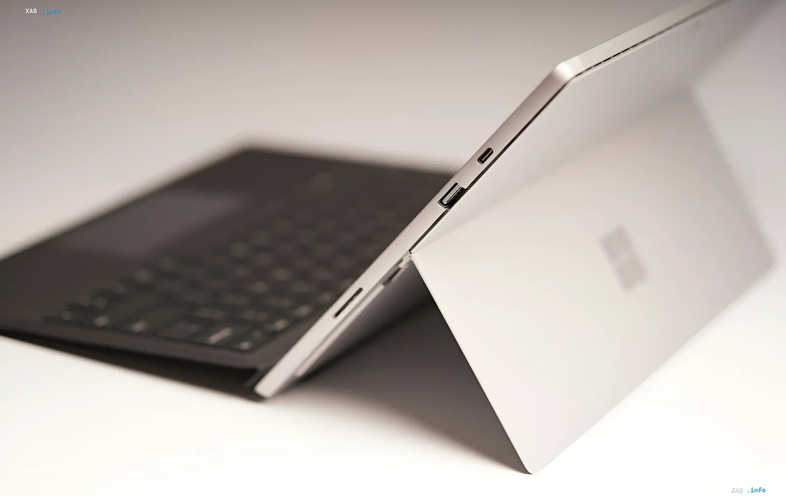 Белый Surface Laptop с видимыми портами USB-C и USB-A, символизирующий разделение Microsoft на бизнес- и потребительские линейки с разными архитектурами процессоров