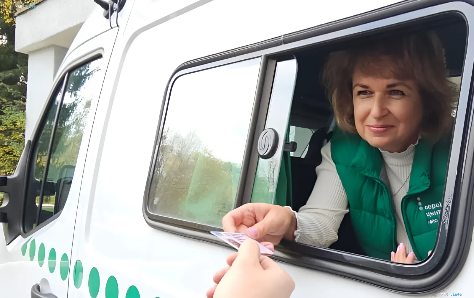 Женщина-водитель в зеленом жилете передает водительские права через окно белого фургона, иллюстрируя новые правила действия прав в Украине — 15 лет