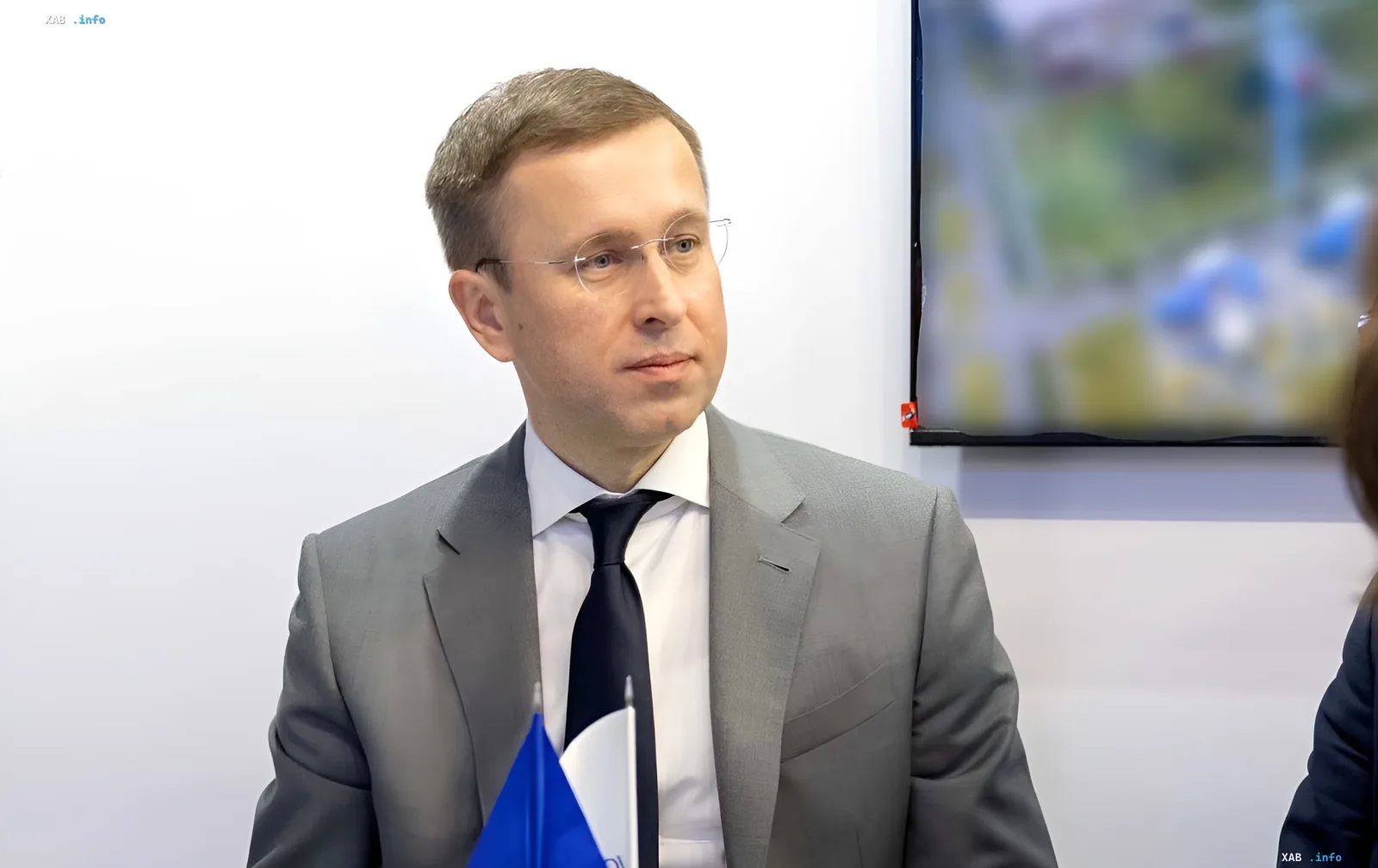 Сергій Корецький у діловому костюмі з прапором України, обговорює можливе призначення на посаду прем'єр-міністра