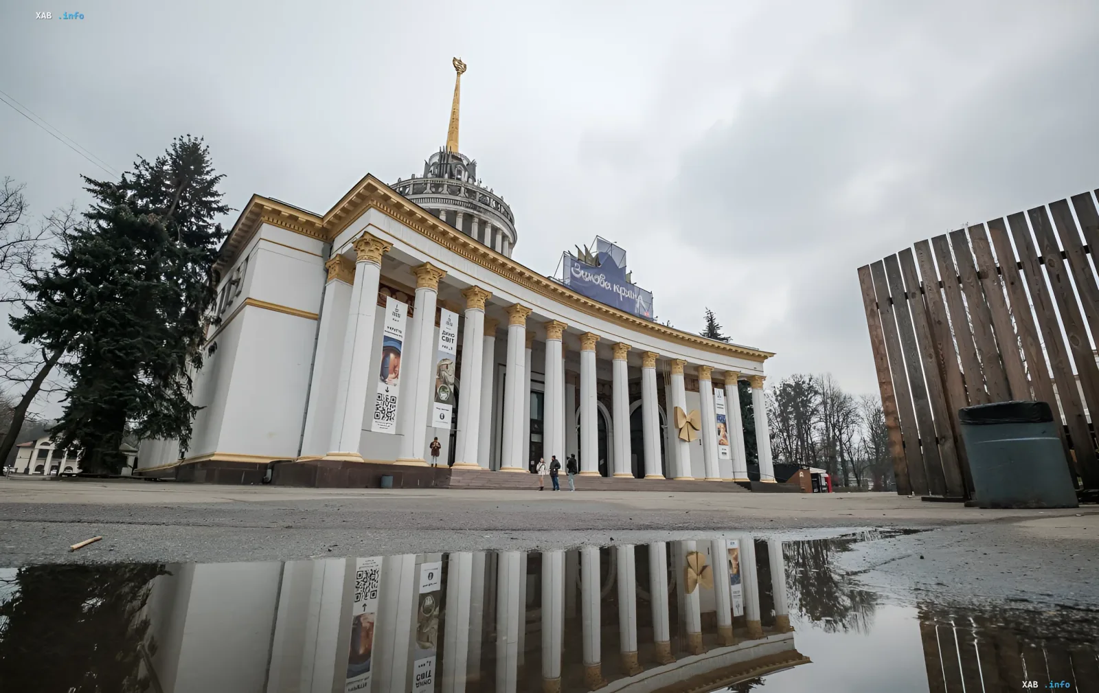 Павильон ВДНХ в Киеве с символом серпа и молота на куполе, отражающийся в луже на асфальте