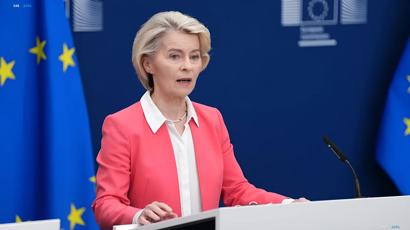 Ursula von der Leyen speaking in front of EU flag, demanding ban on social media for children under 13