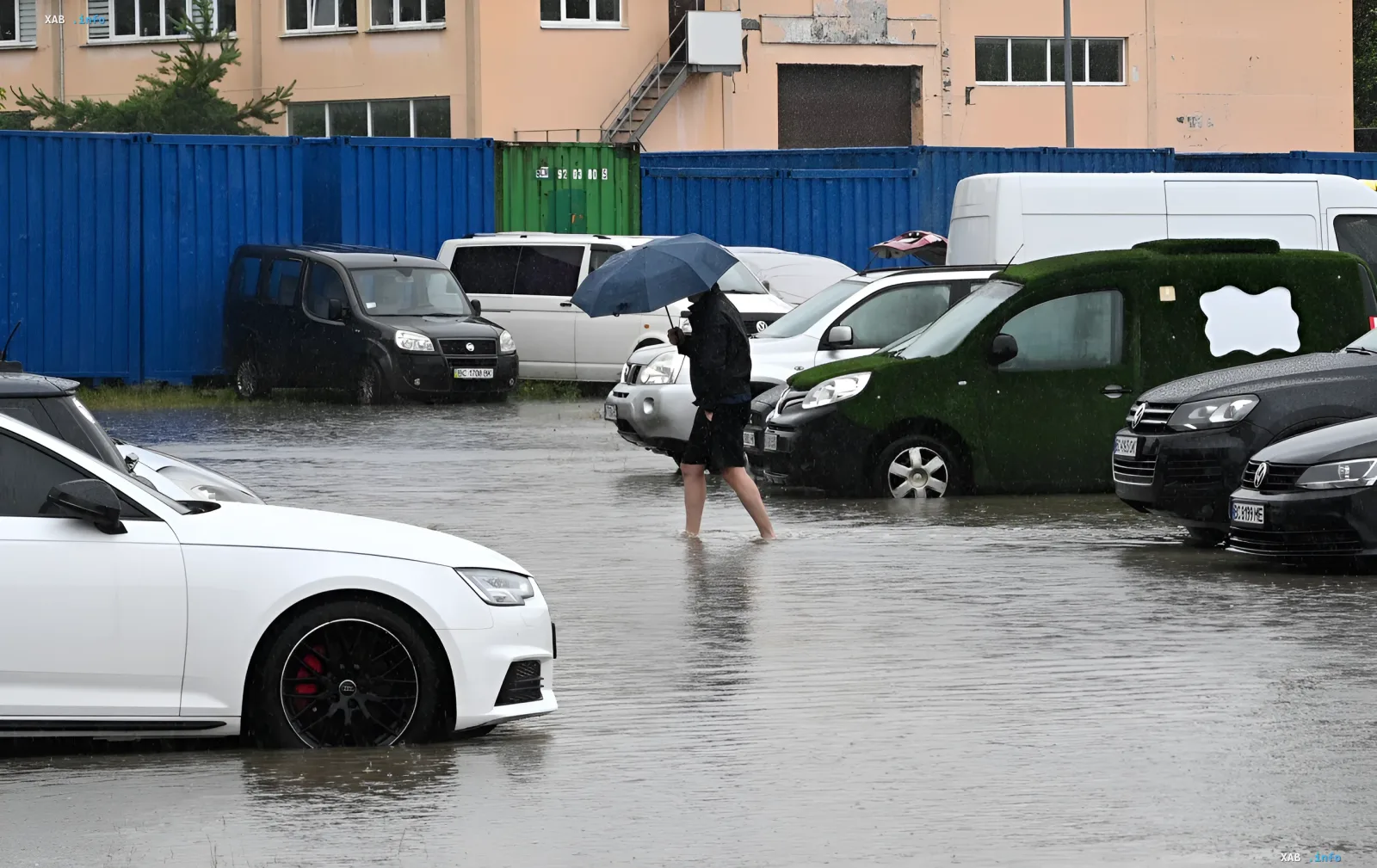 Затопленная парковка во Львове после ливня: автомобили по колесо в воде, человек с зонтом идет через воду