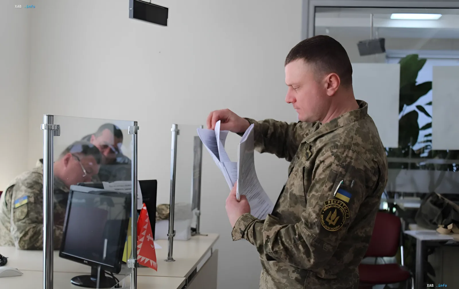 Ukrainian soldier in camouflage reviews documents at a TCC office, symbolizing the extension of mobilization and martial law until 2026