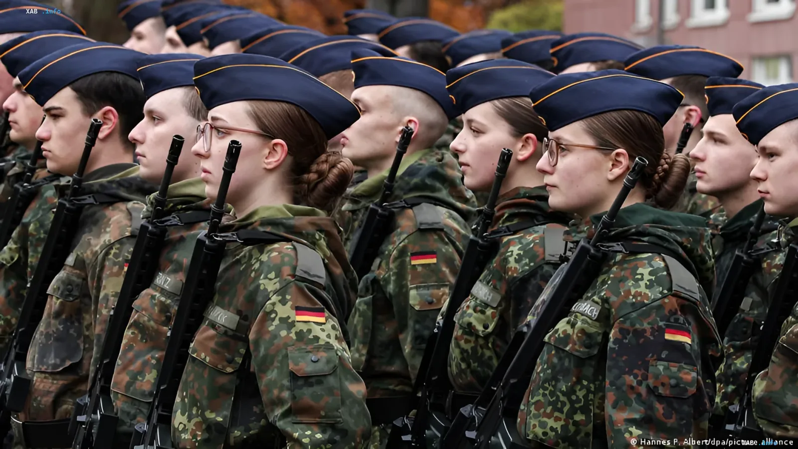 Ряди молодих солдат Бундесверу в камуфляжній формі та синіх беретах з німецькими прапорами на рукавах, що стоять у строю з автоматами, ілюструють реформу армії та зростання відмов від служби серед молоді.