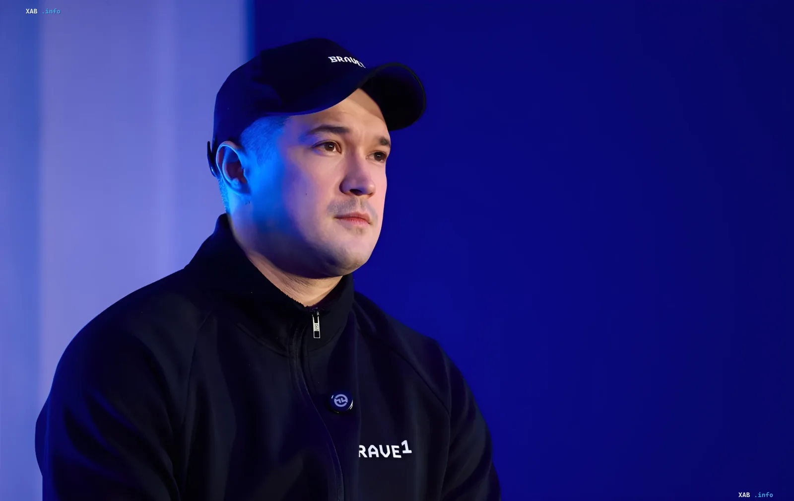 Михайло Федоров у чорній кепці з логотипом BRAVE1 на фоні синього світла, обговорюючи зміну міністра оборони України