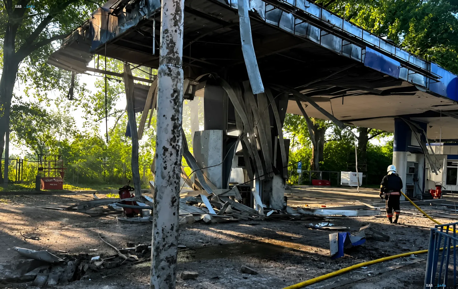 Aftermath of attack on gas station in Zhytomyr region: destroyed roof, debris, and firefighter at the scene