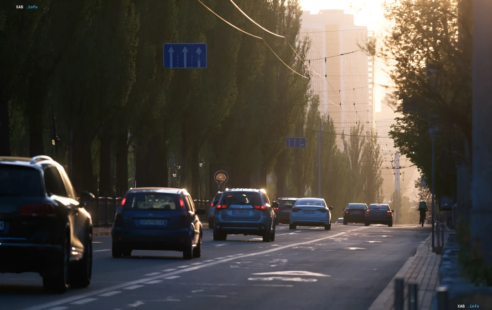 Vehicles driving on a multi-lane road at sunset, illustrating the legality of using the left lane according to traffic rules