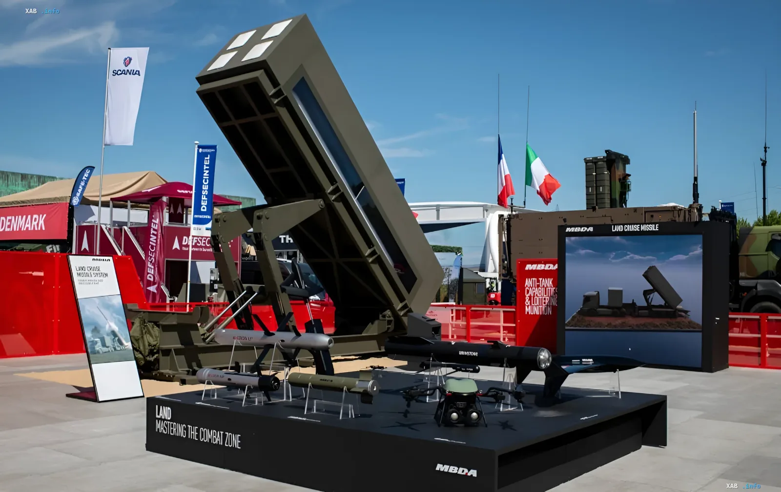 Виставка військової техніки MBDA: мобільний пусковий комплекс крилатої ракети LCM Mk2 з зразками боєприпасів та БПЛА на фоні прапорів Франції та Італії